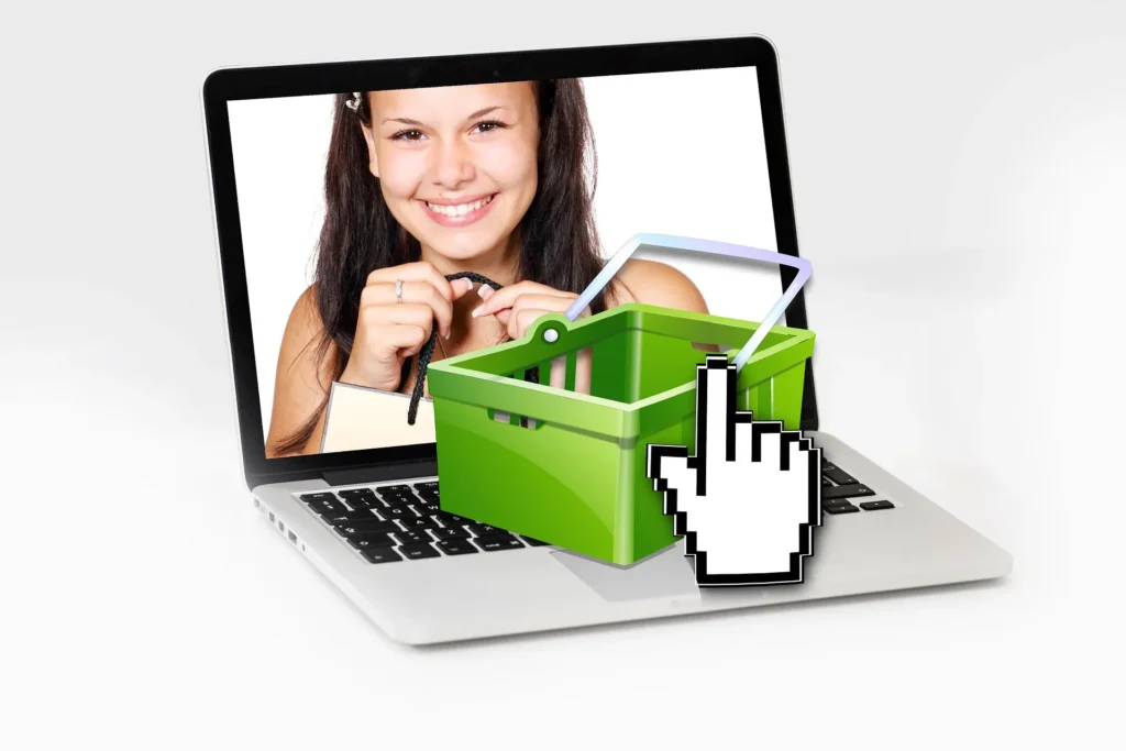 A digital illustration of a smiling woman on a laptop screen behind a 3D green shopping basket and a pixelated hand cursor clicking it.