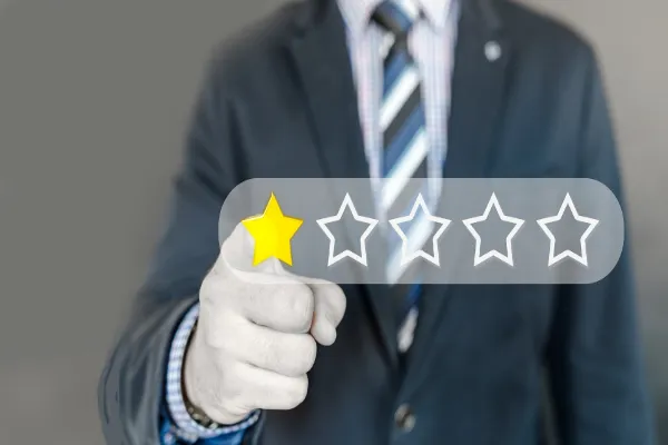 A person in a business suit pointing to a digital rating interface showing a single yellow star out of five, symbolizing a negative or critical review.
