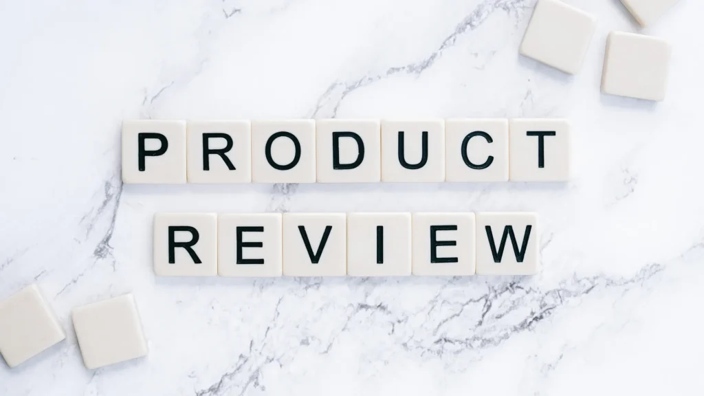 Scrabble-style letter tiles spelling out "PRODUCT REVIEW" on a white marble background with scattered blank tiles.